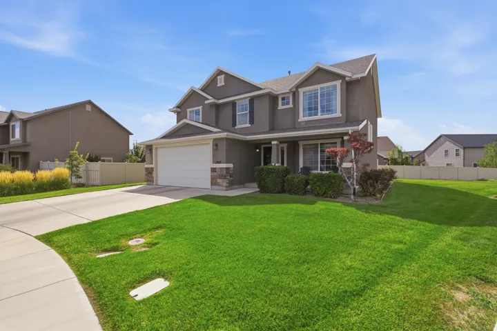 Two-story residence with a stucco exterior, stone veneer accents, an attached garage, and a concrete driveway