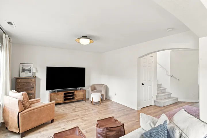 Wood-finish flooring, recessed lighting, arched doorway, and carpeted stairs