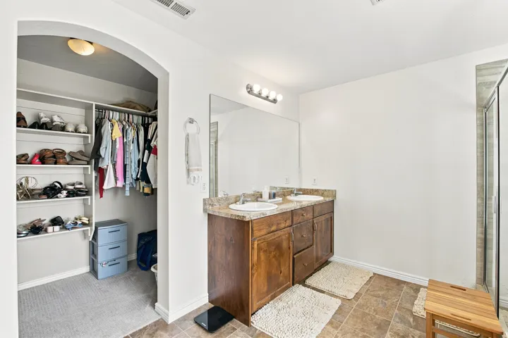 Dual vanity with an integrated countertop, wood-finish cabinetry, and overhead lighting