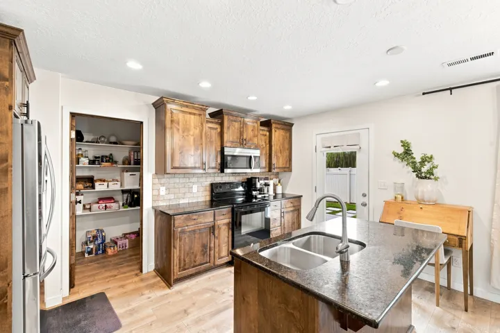 Kitchen featuring wood-finish cabinetry, dark countertops, a tile backsplash, and stainless steel appliances