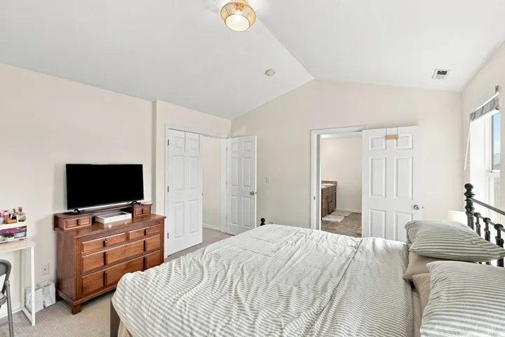 Vaulted ceiling, recessed lighting, neutral wall tones, white paneled doors, and carpet flooring