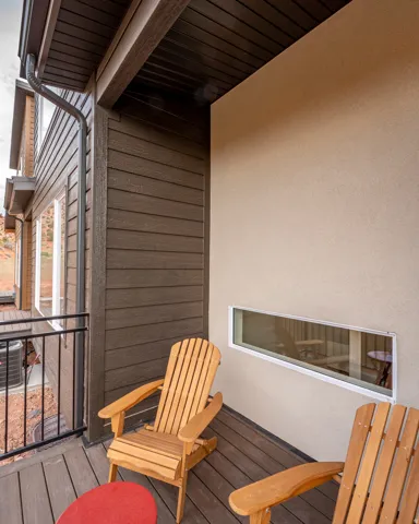 Outdoor balcony featuring composite decking, horizontal siding, black metal railing, and a horizontal window