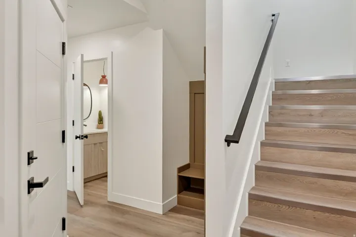 Wood-finish flooring with a modern staircase featuring a black metal handrail and integrated lighting