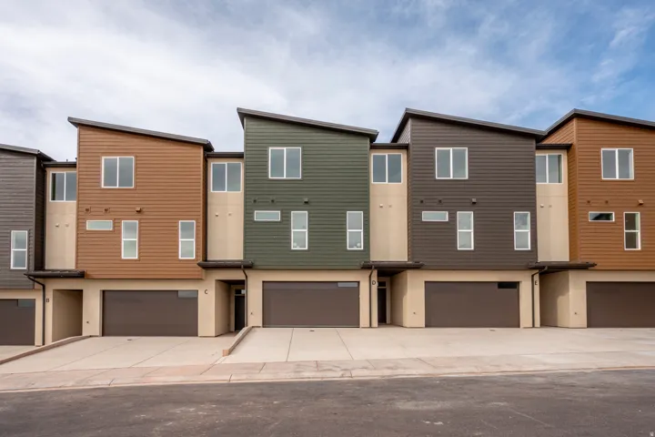 Modern townhome architecture featuring varied siding textures, multiple windows, integrated garage doors, and a distinct roofline