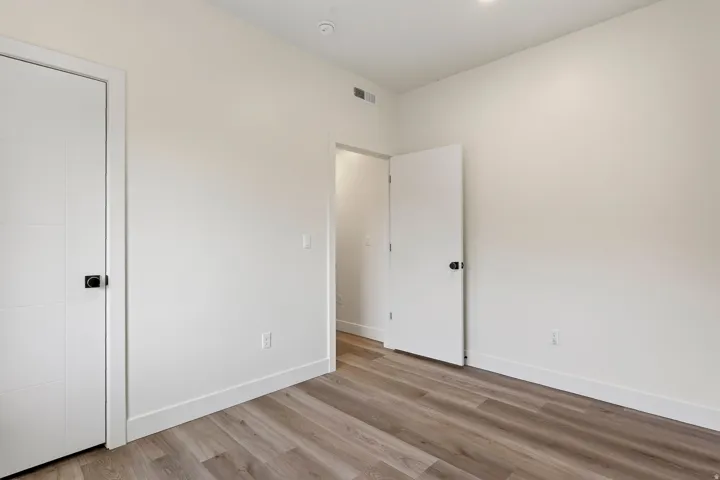 Recessed lighting, wood-finish flooring, white trim, and white interior doors with contemporary black hardware