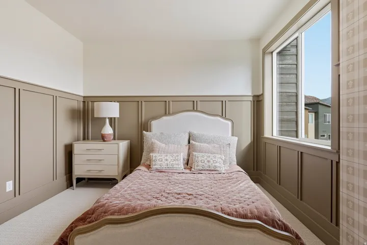 Board and batten wainscoting with a neutral color palette, complemented by a large window providing natural light, and plush carpet flooring