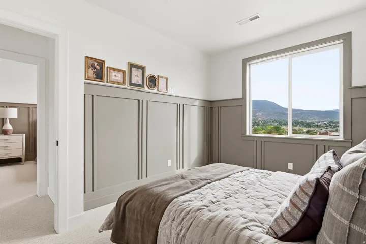 Architectural paneling accent wall, large window with mountain scenery, plush carpet flooring, recessed ceiling vent