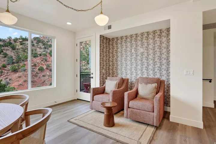 Expansive window with mountain scenery, glass panel door to outdoor space, wood-finish flooring, recessed lighting, and decorative accent wall