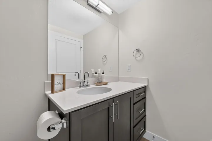Built-in vanity with a white countertop, undermount sink, chrome faucet, and dark wood-finish cabinetry