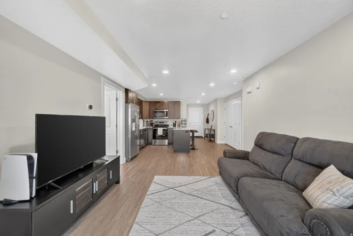 Open-concept living space featuring wood-finish flooring, recessed lighting, and a modern kitchen with stainless steel appliances and dark wood cabinetry
