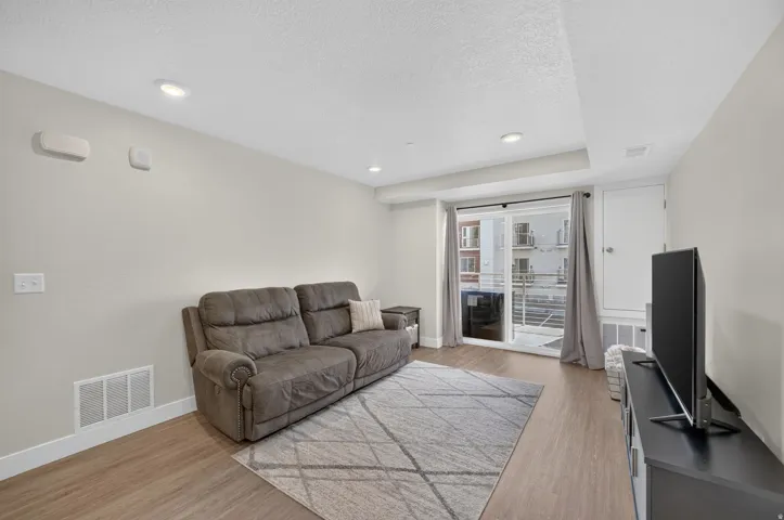 Recessed lighting, wood-finish flooring, sliding glass door, and a built-in storage cabinet