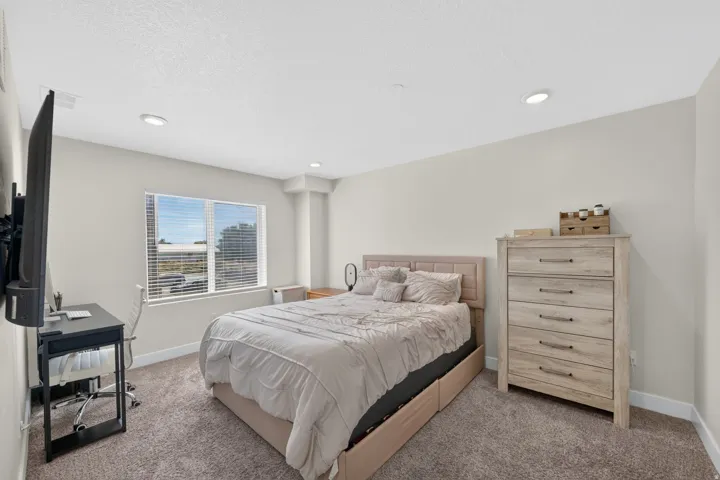Recessed lighting, light-toned carpeting, a window with horizontal blinds, and neutral wall tones