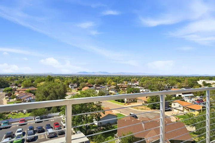 Balcony with horizontal metal railing overlooking a residential area with distant mountains
