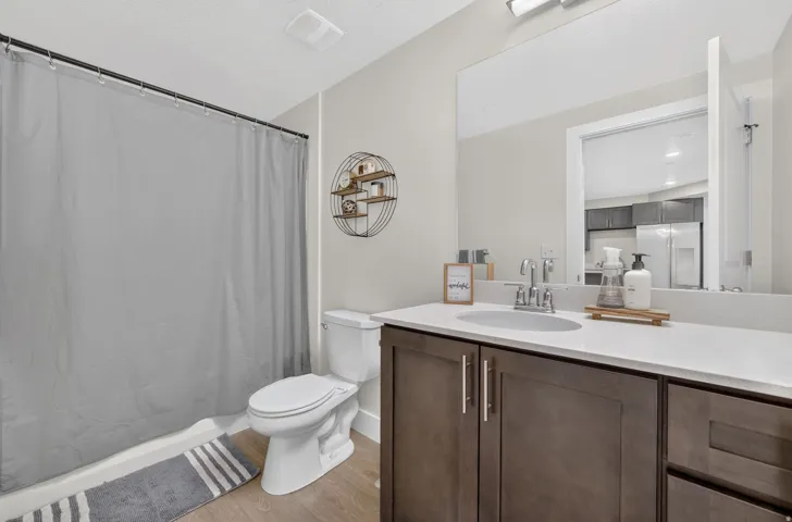 Bathroom featuring a single vanity with dark wood-finish cabinetry, a white countertop, a drop-in sink, and a wall-mounted mirror