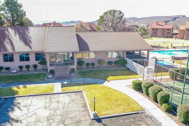 Tile roof building with covered entry, adjacent to a swimming pool and tennis court