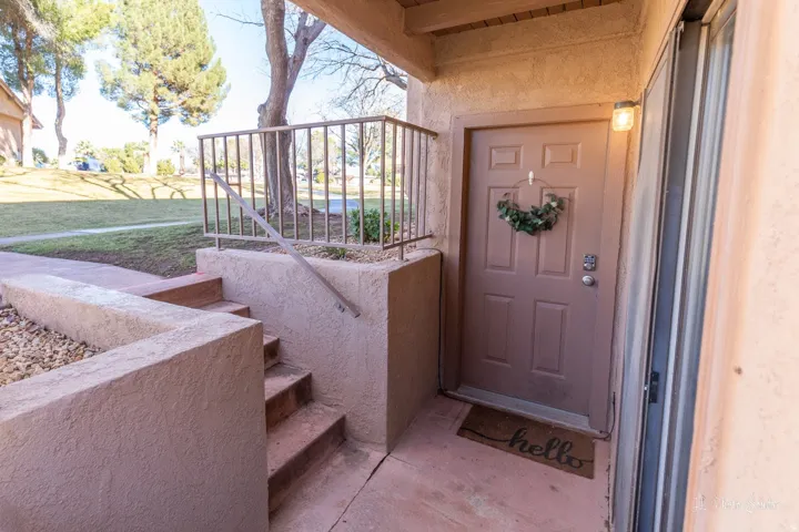 Stucco exterior with concrete stairs and a metal railing