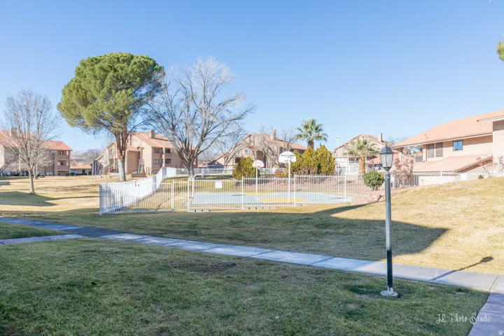 Expansive green spaces and mature trees surround the property, featuring a fenced basketball court