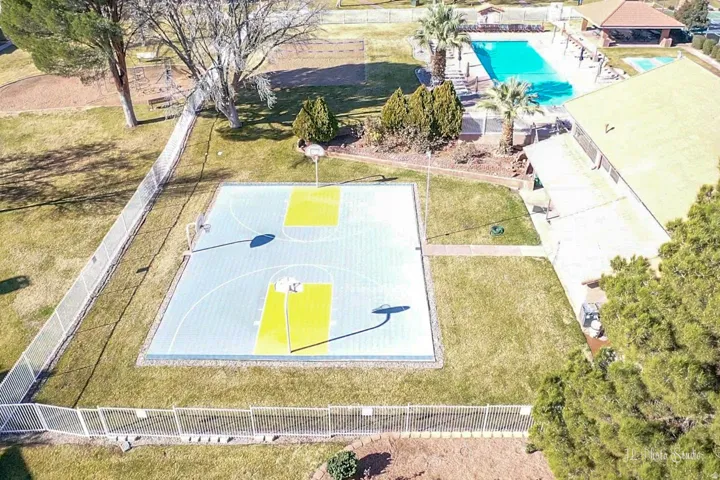 Recreational area featuring a basketball court, swimming pool, and a building with a covered patio