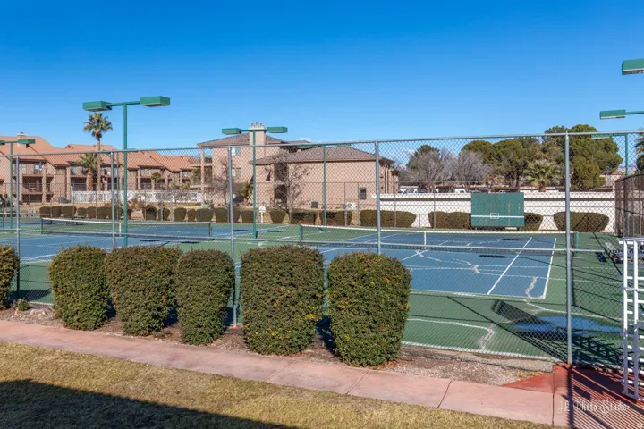 Outdoor tennis courts featuring perimeter fencing and court lighting