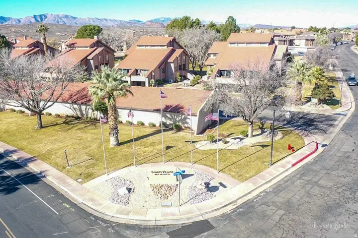 Community entrance with a landscaped corner, mature palm trees, and a monument sign