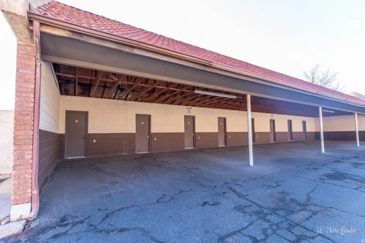 Covered exterior walkway with multiple entry doors, brick column, and tiled roofline