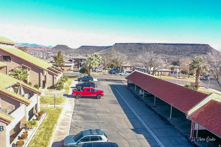 Covered parking structures with red-tiled roofs, complex exterior featuring individual patios, and distant mountain scenery