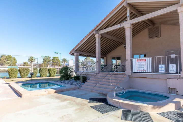 Outdoor spa, covered patio, steps with handrails, and a nearby tennis court