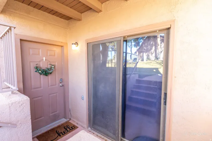 Exterior entryway featuring a paneled door, a wall-mounted light fixture, and a sliding glass door