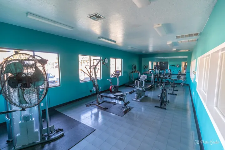 Fitness room featuring multiple exercise machines, mirrored wall, large windows, and tile flooring
