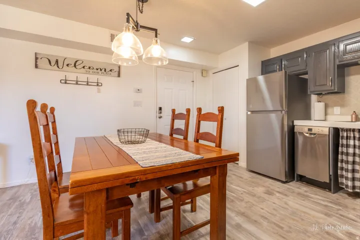 Open-concept kitchen and dining area featuring wood-finish flooring, stainless steel appliances, dark cabinetry, and recessed lighting