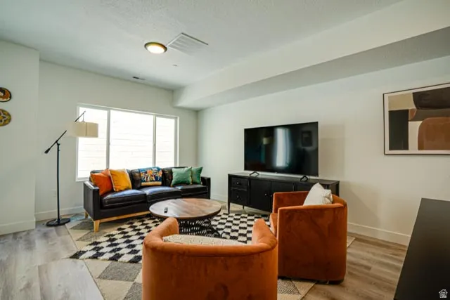 Recessed lighting, large window with ample natural light, modern wood-finish flooring, white walls, and a built-in media console