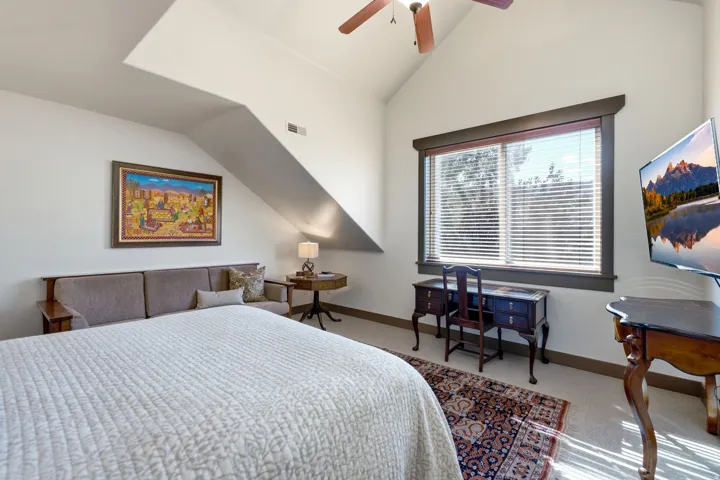 Vaulted ceiling with a ceiling fan, a large window with blinds, and light-colored carpet