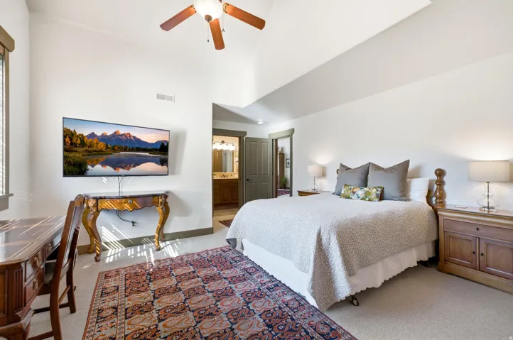 Vaulted ceilings with a ceiling fan, carpeted flooring, and a built-in wall-mounted television