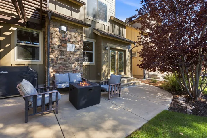Concrete patio with a built-in fire pit, stone accent wall, and pergola