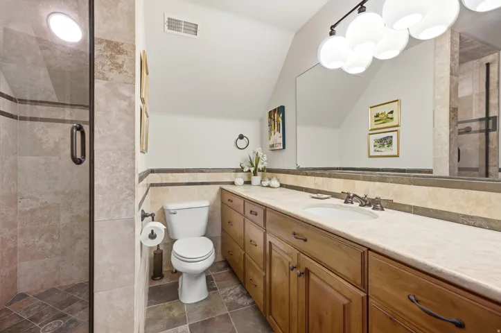 Walk-in shower with clear glass enclosure and tile surround