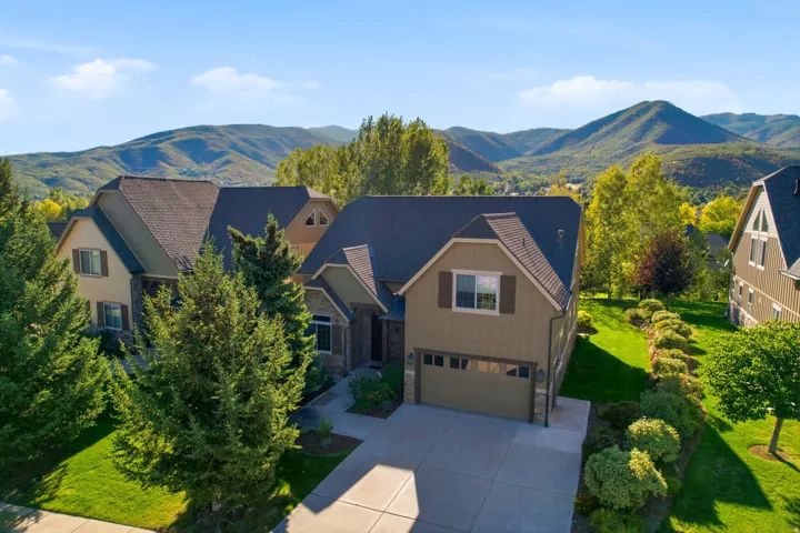 Contemporary residence featuring a two-car garage, stone accents, and a paved driveway