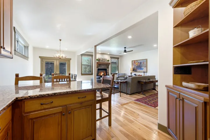 Kitchen island with a stone countertop, wood-finish cabinetry, and wood-finish flooring