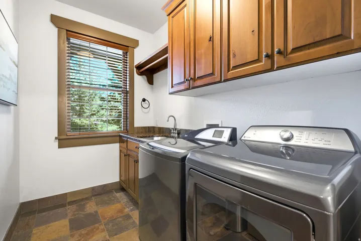 Warm wood cabinetry, stone-look tile flooring, and a window with wood-look blinds