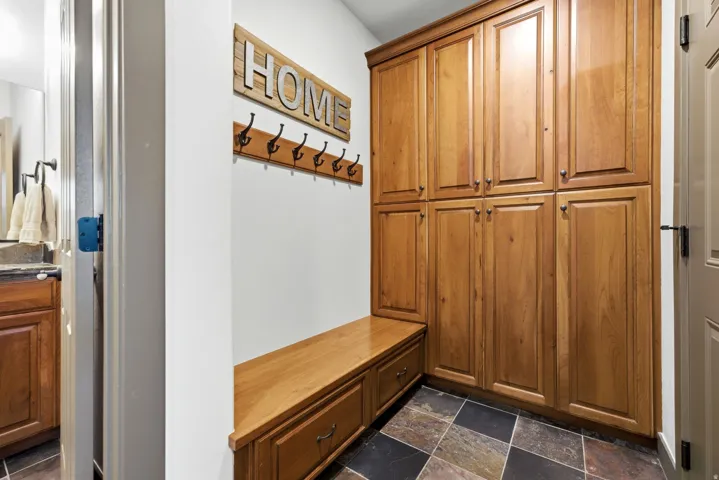 Full-height wood cabinetry, built-in wood bench with storage drawers, and durable multi-tone floor tiling