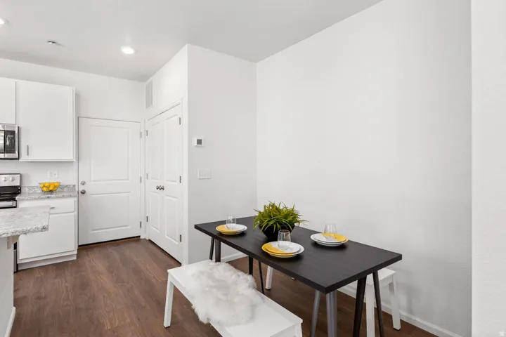 Kitchen area with white cabinetry, stainless steel microwave, and wood-finish flooring