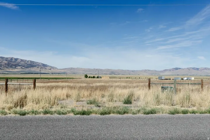 Expansive agricultural land featuring a wire fence, natural grassland, and distant mountain ranges