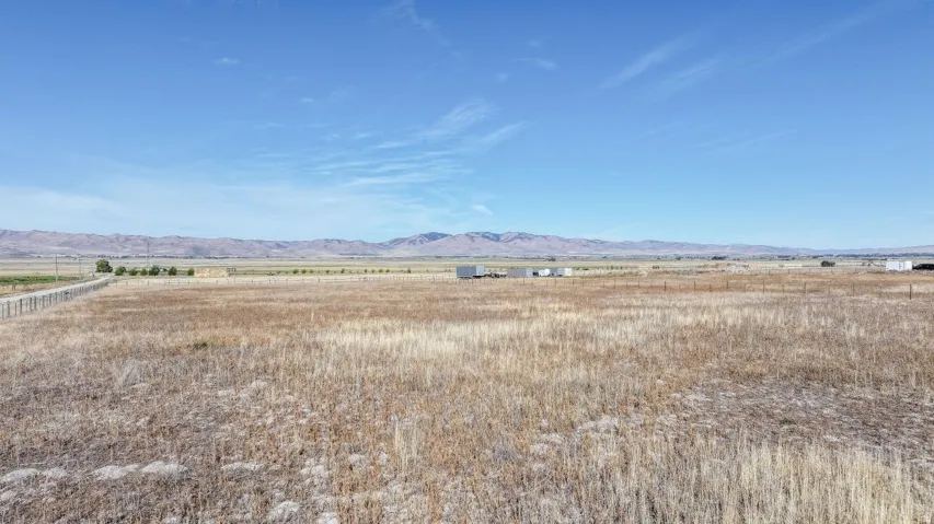 Expansive open field with scattered buildings and distant mountain ranges