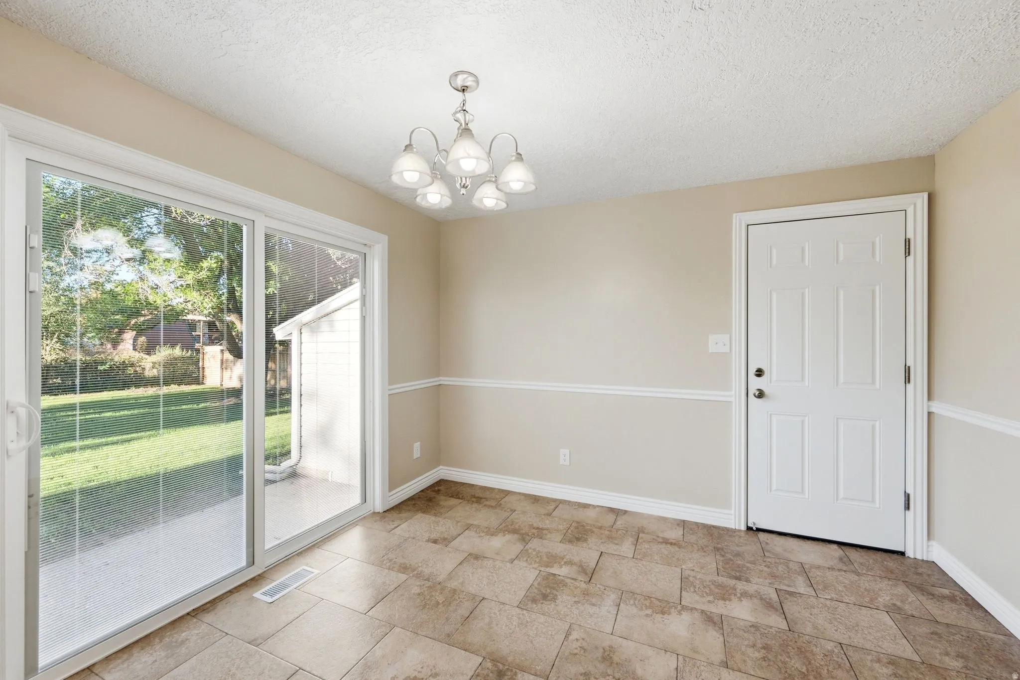 Sliding glass door, tiled flooring, overhead light fixture, white interior door, and wainscoting