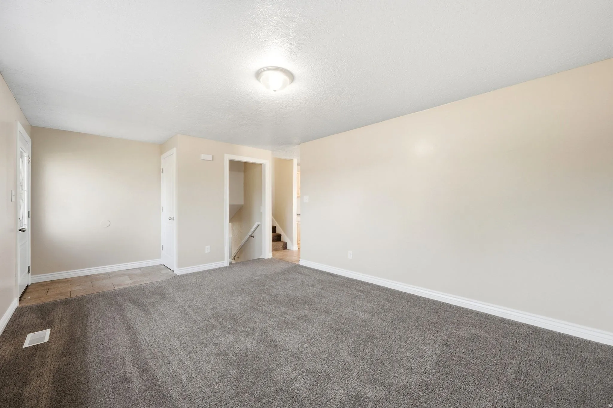 Spacious room with plush gray carpeting and light-toned walls