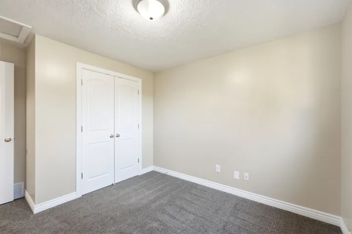 Neutral wall paint, textured ceiling, flush mount ceiling light, and gray patterned carpeting