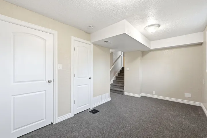 Plush gray carpeting, white interior doors, recessed lighting, and a neutral wall color