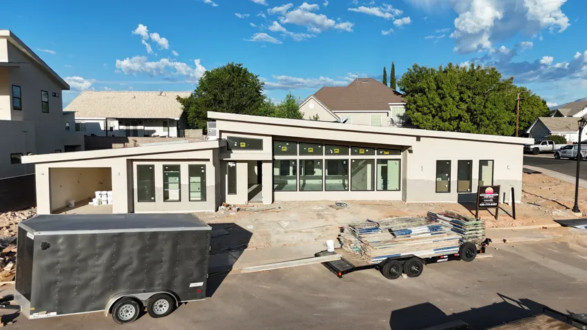Modern-style exterior with a clean stucco finish, multiple large windows, a covered entrance, and a flat roof design
