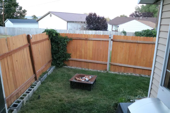 Gated outdoor area with a wood privacy fence and a fire pit
