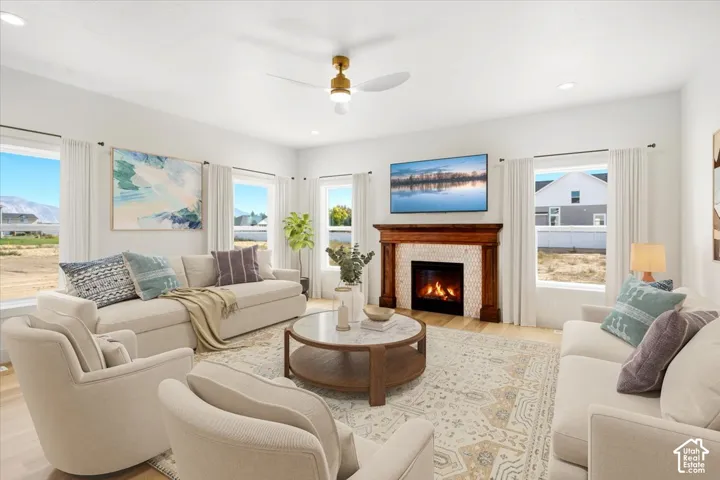 Living area featuring a fireplace with a wood mantel and patterned tile surround, recessed lighting, wood-finish flooring, and a central ceiling fan