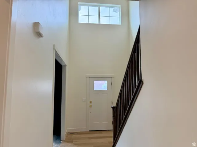 Two-story entryway with a transom window, wood-finish flooring, and a dark wood staircase
